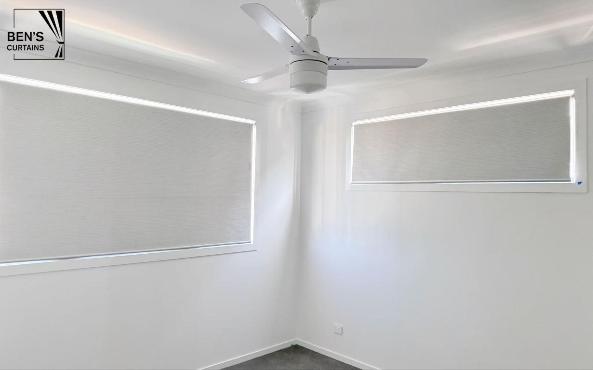 White blockout roller blinds installed within the window frame in a bedroom
