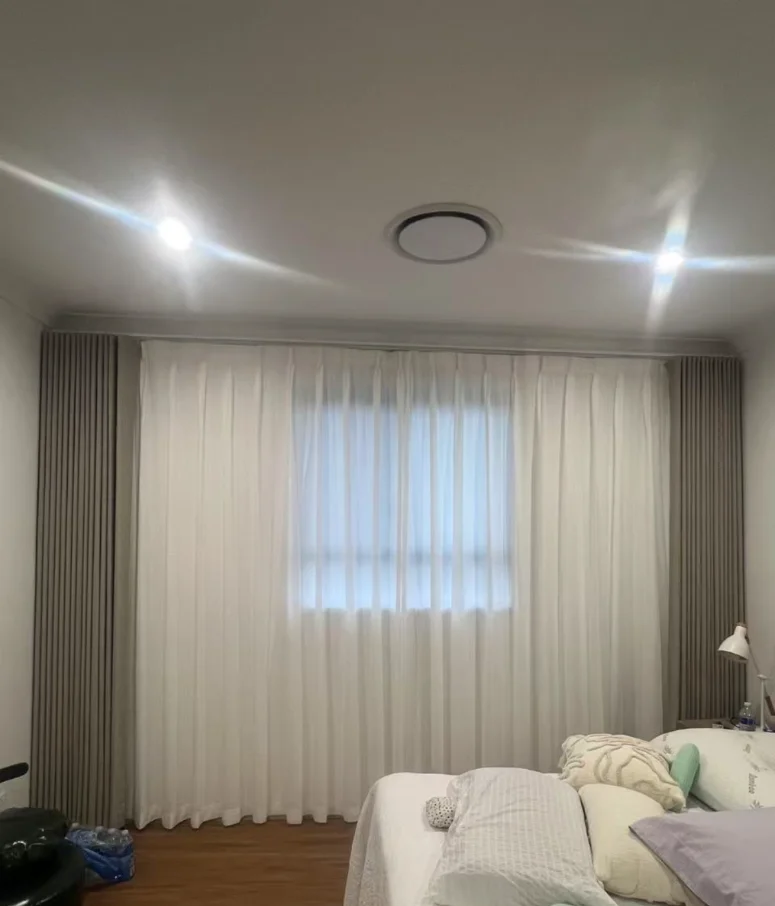 S-fold blockout brown curtain with pinch privacy sheer installed for one window in the bed