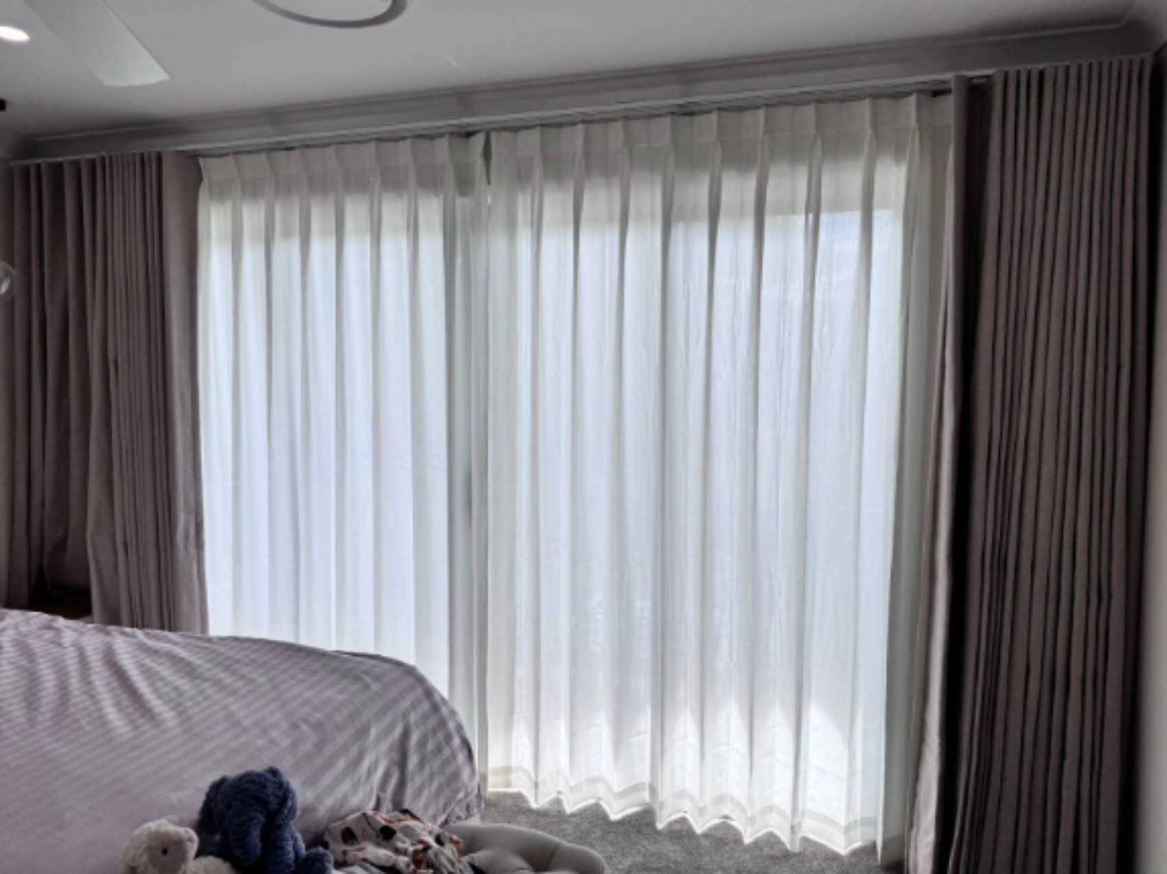 Grey S-fold blockout curtain and pinch privacy sheer installed in the bedroom