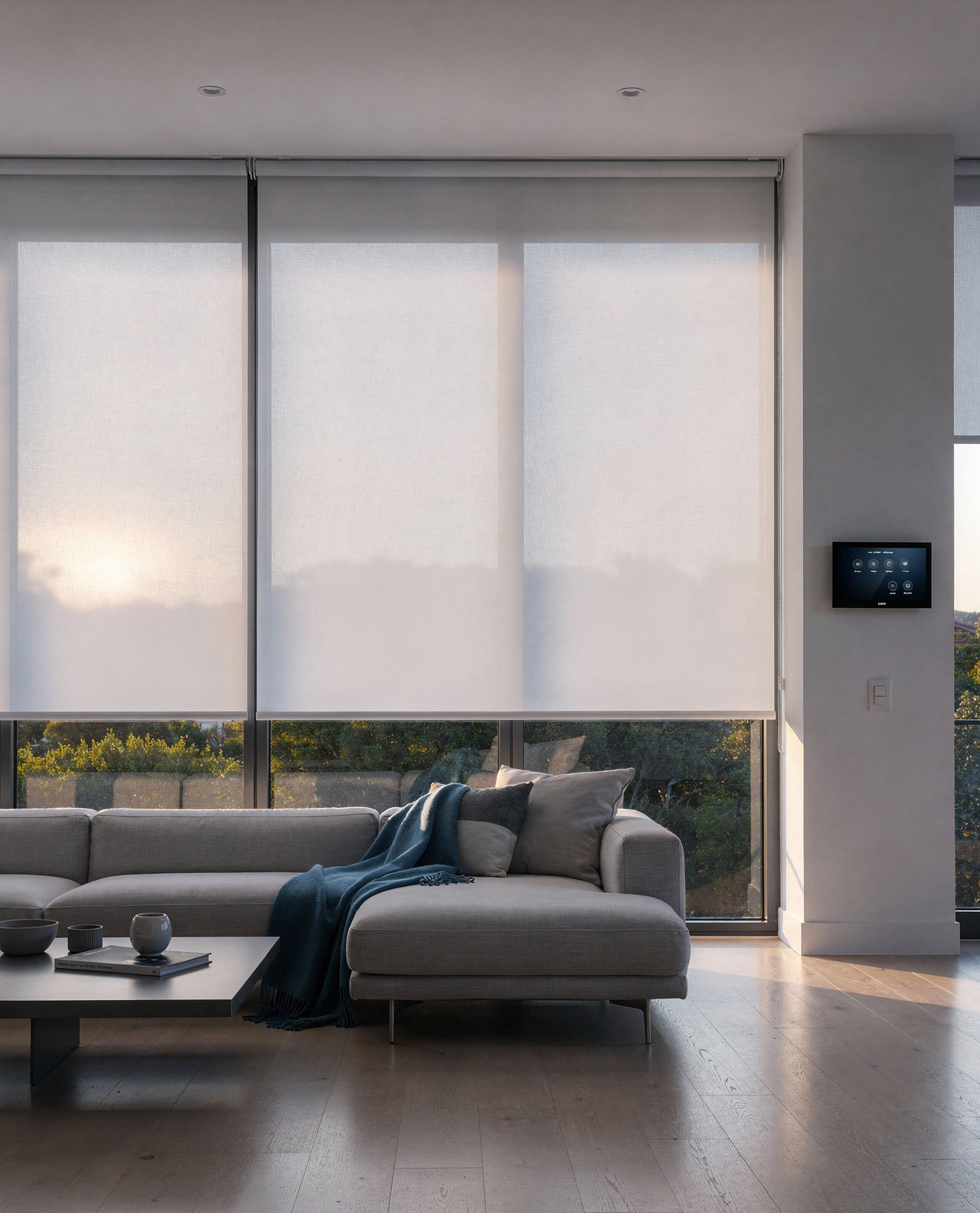 Motorised roller blinds lowered in even alignment across large windows with a smart wall control panel beside them