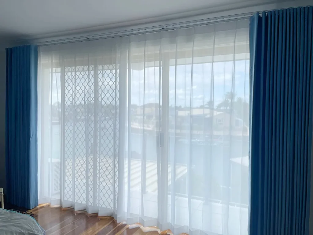 Blue S-fold curtains with white sheer panels, elegantly draped over a window.