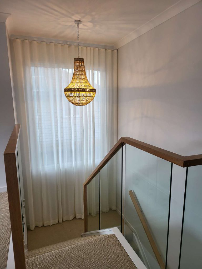 S-fold transparent sheers elegantly installed on a staircase window.