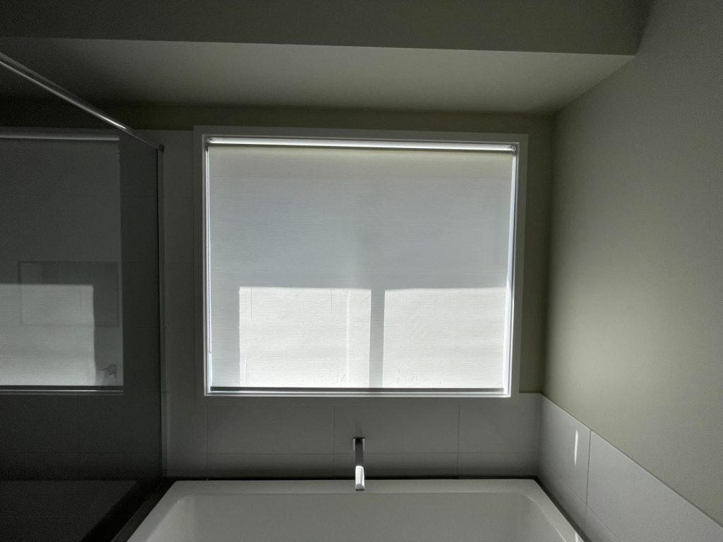 White sunscreen roller blinds elegantly installed in a bathroom.