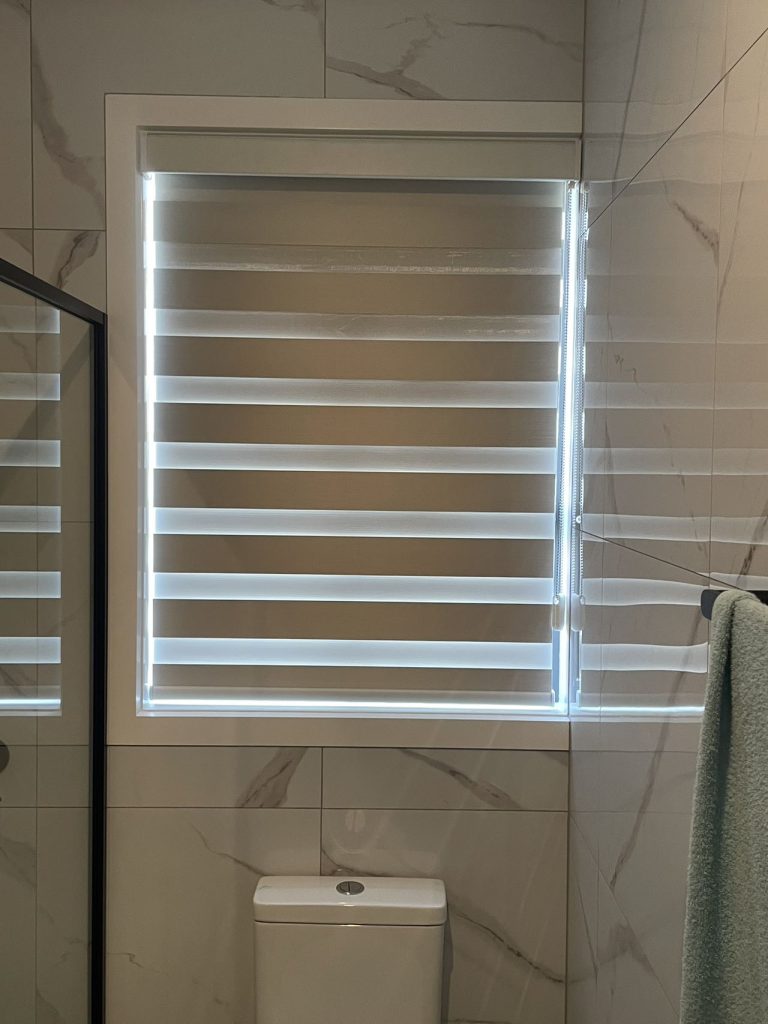 Beige zebra roller blinds elegantly installed in a bathroom