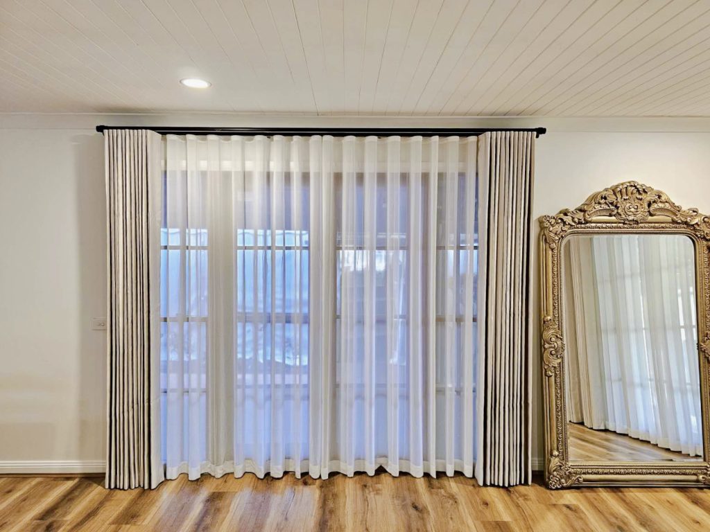 Silver S-fold curtains and transparent sheers on a rod track.