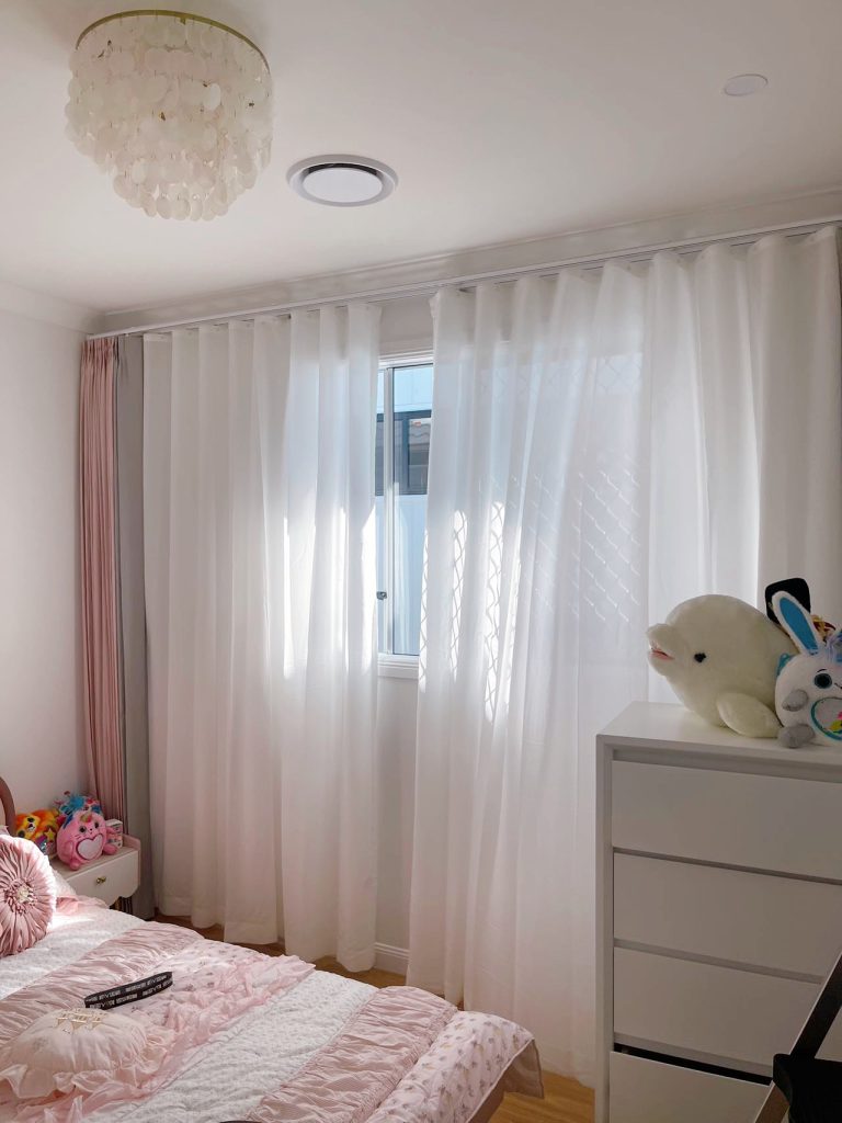 Pink pinch pleat curtains paired with S-fold privacy sheers.