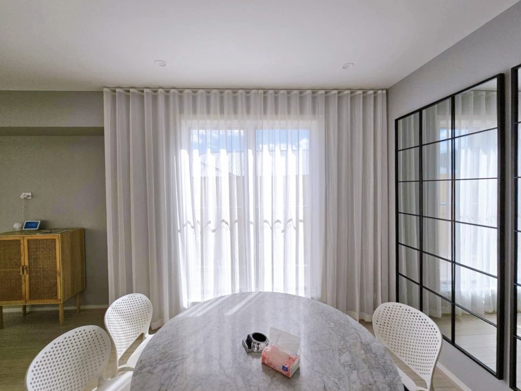 S-fold privacy sheers elegantly installed in a dining room.