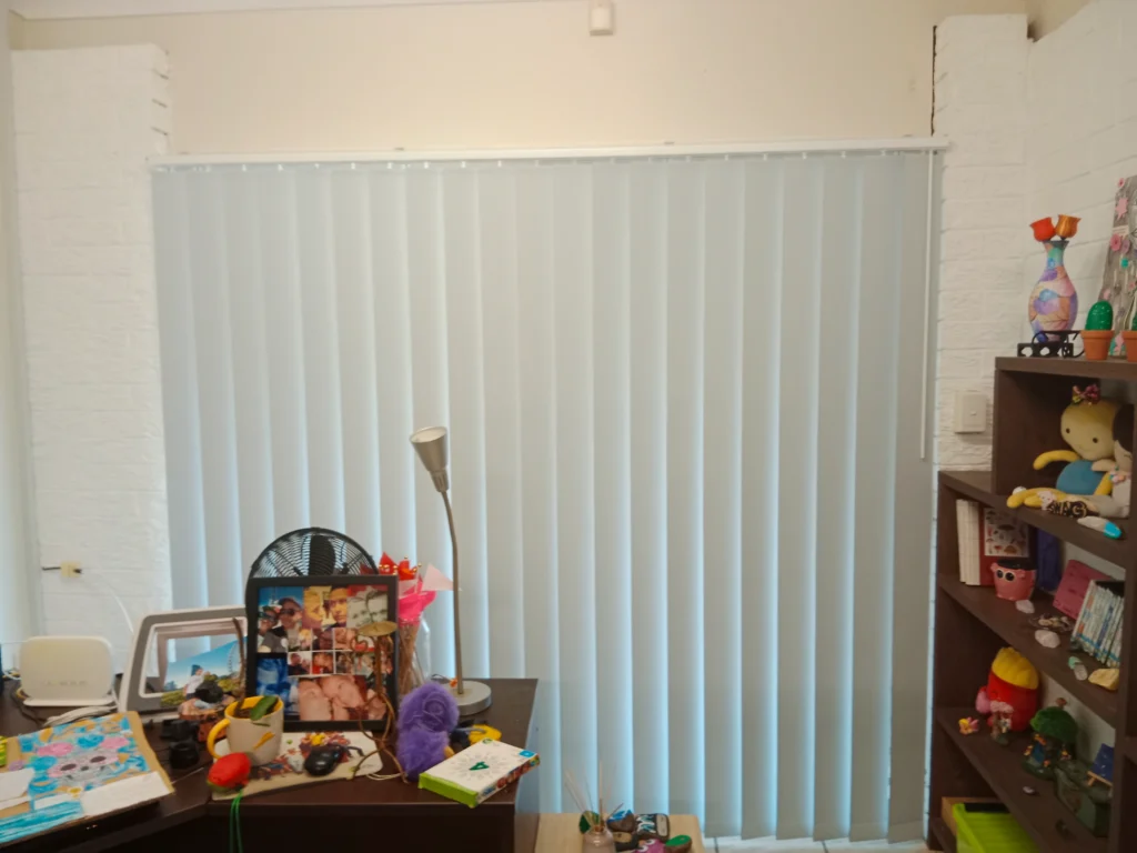 white vertical blind installed for one window in bedroom